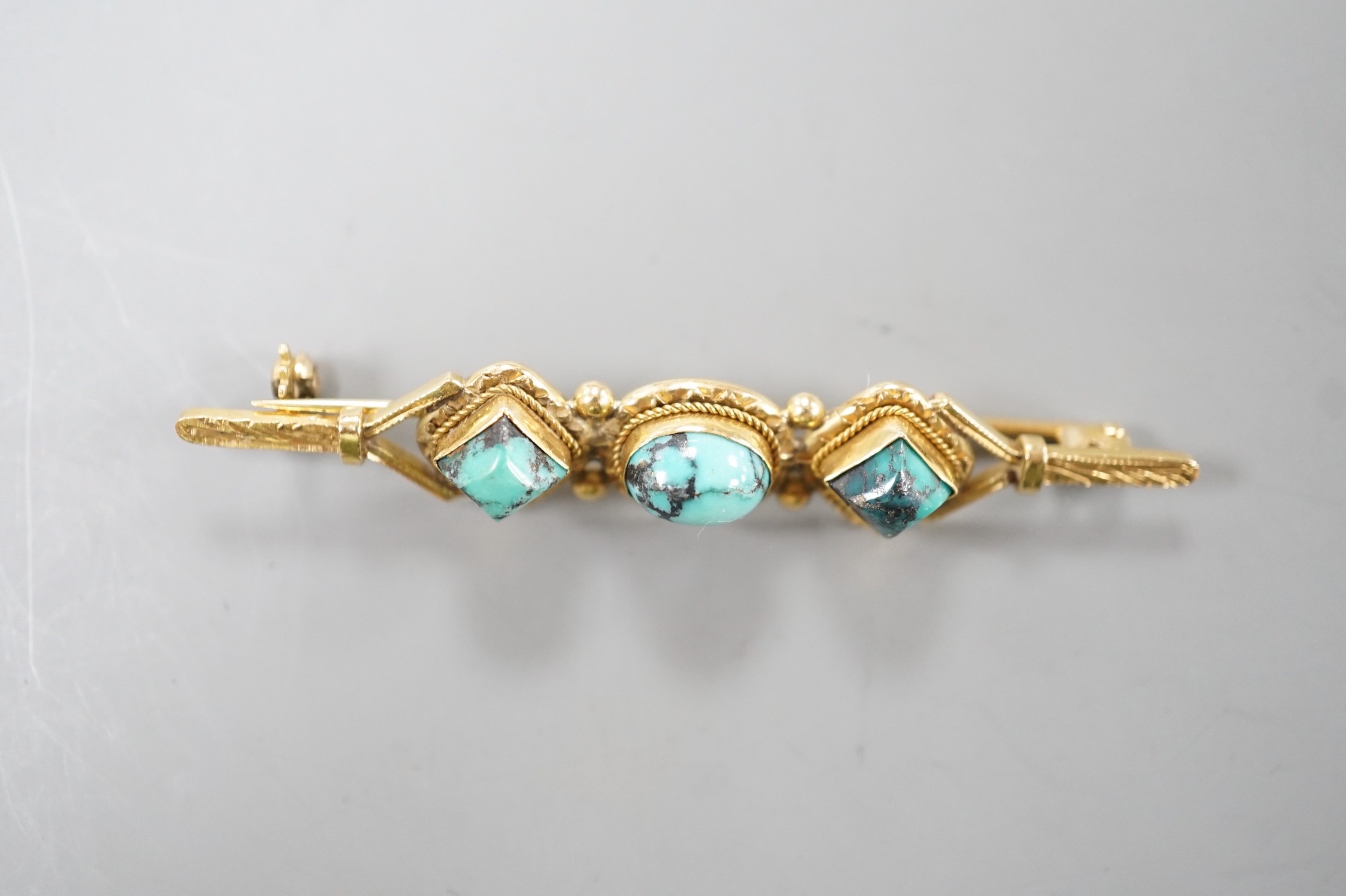 A 750 yellow metal and three stone shaped turquoise set bar brooch, 57mm, gross weight 6.6 grams.
